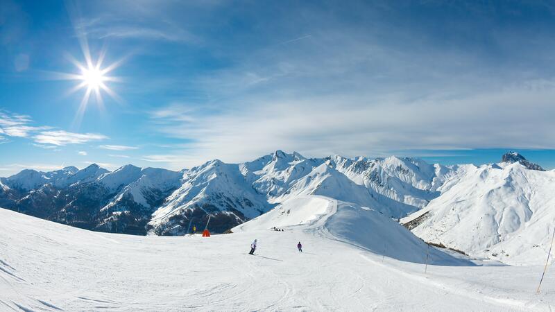 Skiers on the slopes surrounded by mountains and snow